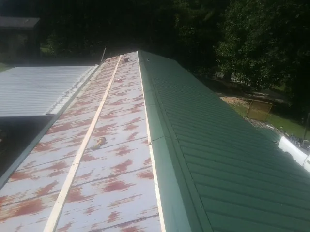 Old rusted panels beside newly installed green metal roofing — Wind Damage Roof Repair by Roofing Brothers in Mystic