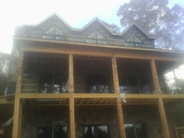 Dormers and porch framing on a large log home under construction — Roof Coating work by our crew in Mystic